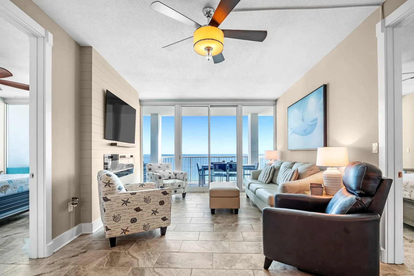 Gulf Shores living room with ocean views through glass doors, coastal seating and a balcony dining table